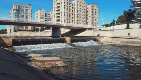 Avanzar-Hacia-La-Pequeña-Cascada-Debajo-Del-Puente-En-La-Ciudad,-Montpellier---Francia