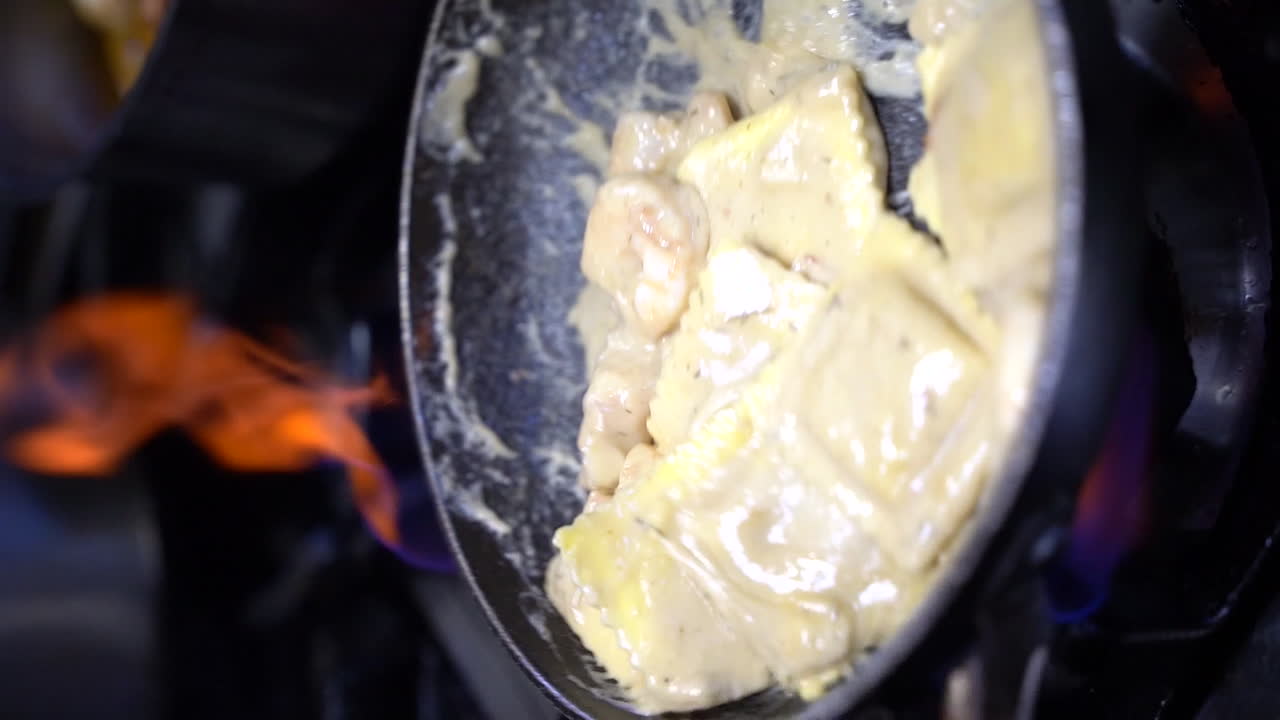 Cooking ravioli with shrimp in sour cream in cooking pan