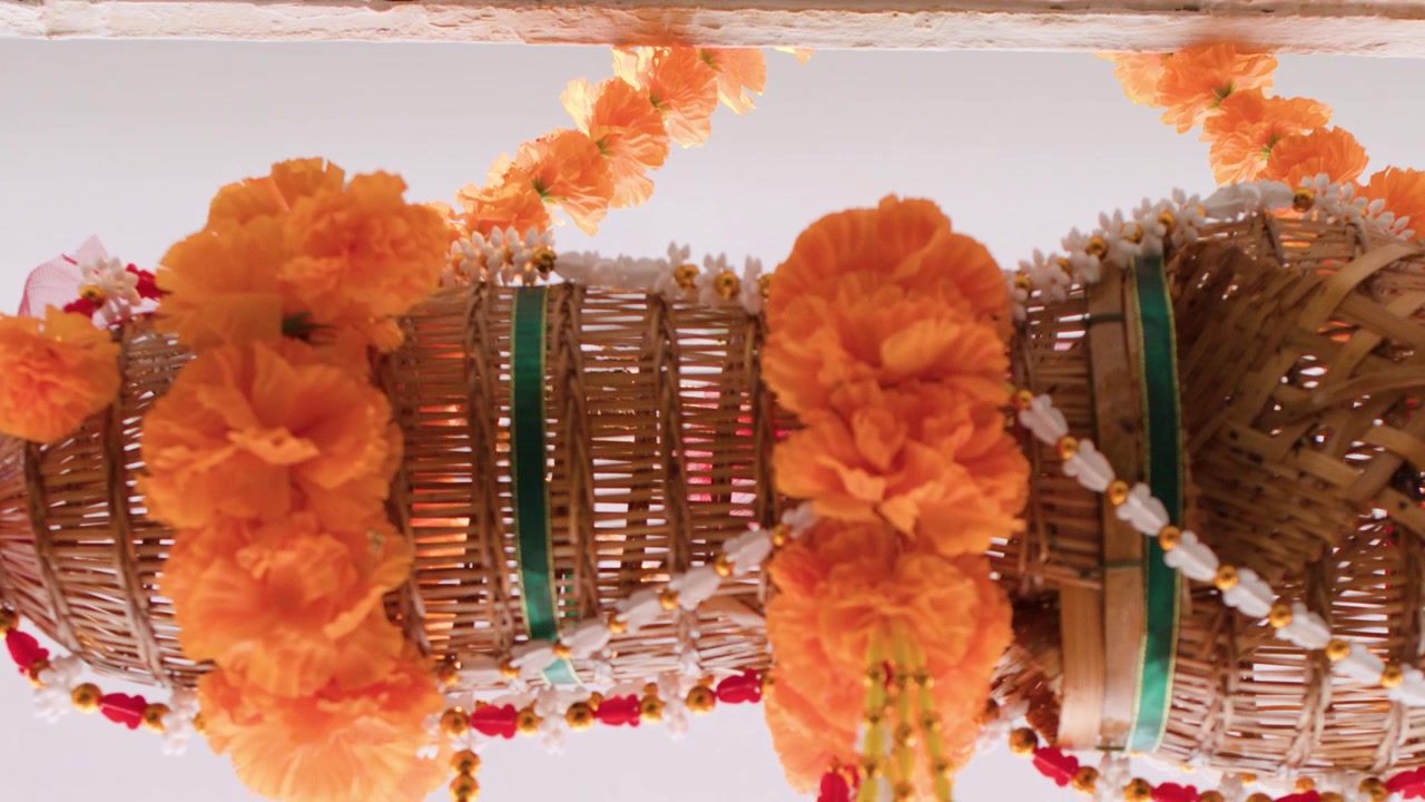 Ripresa in movimento dal basso di una nassa di bambù intrecciata adornata con fiori di calendula arancioni.