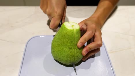 person slicing a pear on a cutting board