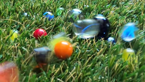las canicas de colores aterrizan y chocan durante un juego sobre césped verde artificial