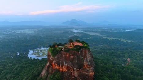 numerous tourists walk by the ruins of fortress sigiriya in sri lanka. lion rock from top view with hazy scenery at backdrop.