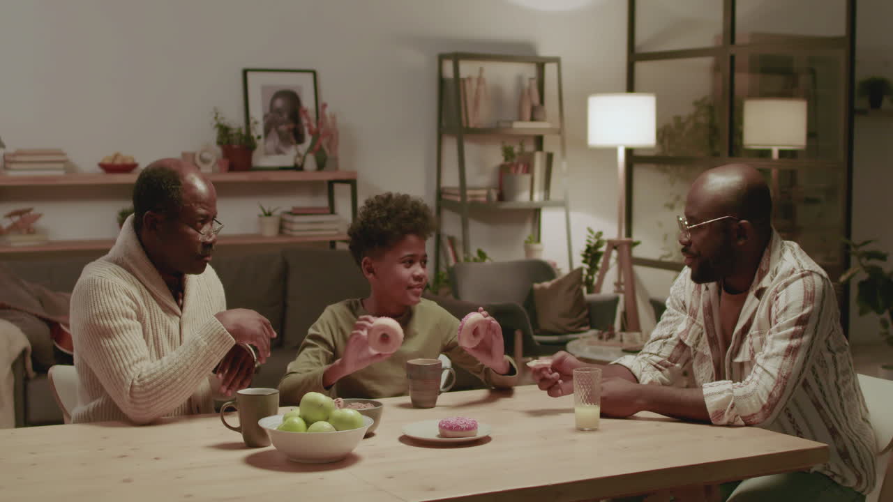 Black men and boy having fun while eating at home