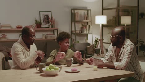 black men and boy having fun while eating at home