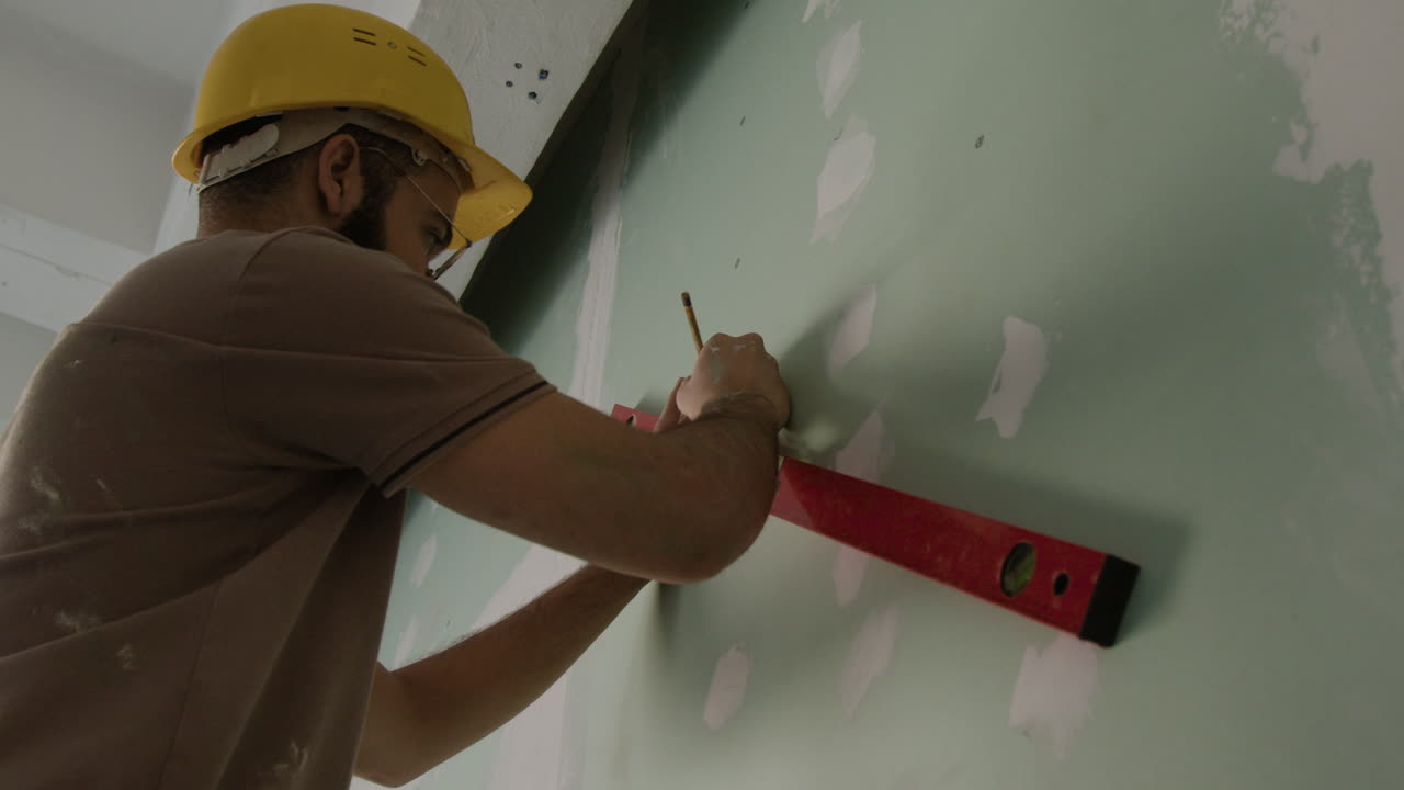 Construction worker using a level on a wall