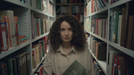 retrato de una chica de cabello rizado sosteniendo un libro en el pasillo de la biblioteca