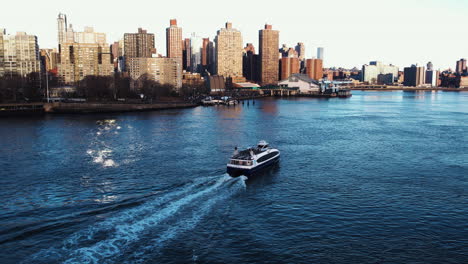 Aerial-view-towards-a-ferry-on-the-East-river,-golden-hour-in-Manhattan,-NY,-USA