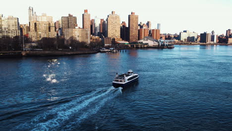 aerial view towards a ferry on the east river, golden hour in manhattan, ny, usa