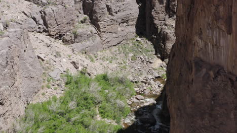 A-stunning-view-from-the-top-of-a-steep-cliff-overlooking-a-deep-canyon-gorge-with-fast-flowing-white-water