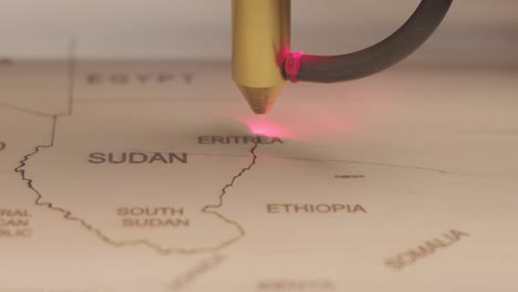 cnc laser cutting machine cuts world map on wooden plank and plywood