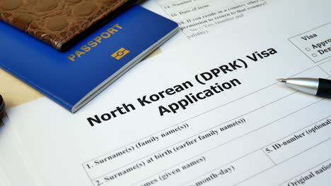 formulario de solicitud de visado de corea del norte con pasaporte y bolígrafo