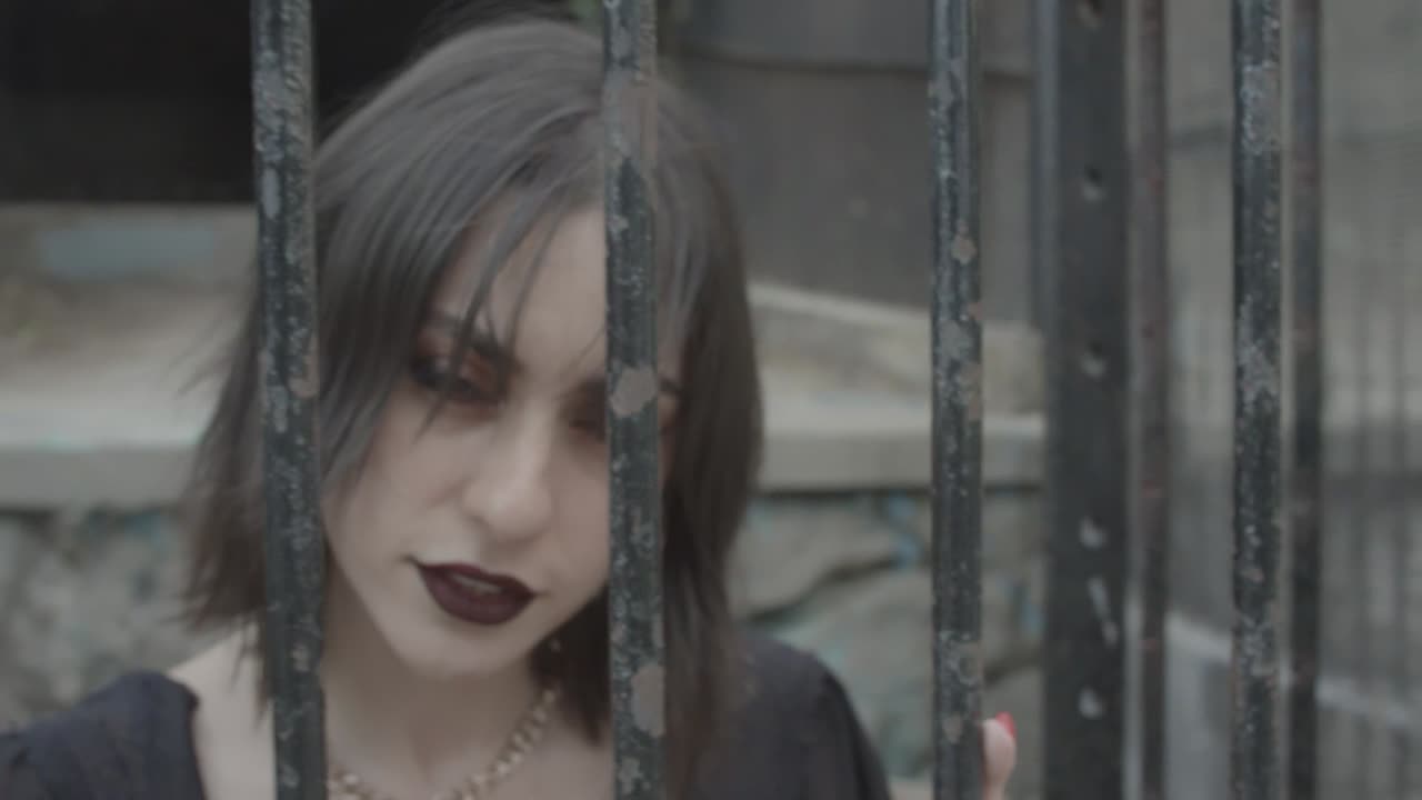 mujer espeluznante moviéndose lentamente dentro de barras de metal viejas y oxidadas mientras mira sin miedo en la cámara, - aleje el zoom
