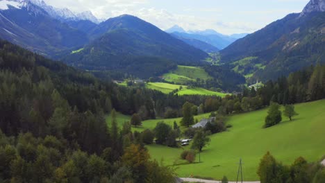 A-birds-eye-view-of-a-mountain-valley-with-some-houses-in-the-bottom-surrounded-by-forest