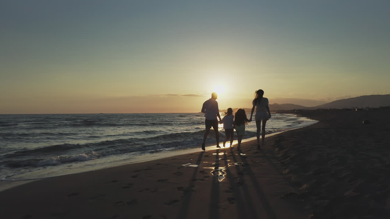 해가 지면 해변에서 달리는 가족