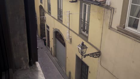 a view looking down into a narrow alleyway in florence, italy, featuring a vintage street lantern mounted on a building.