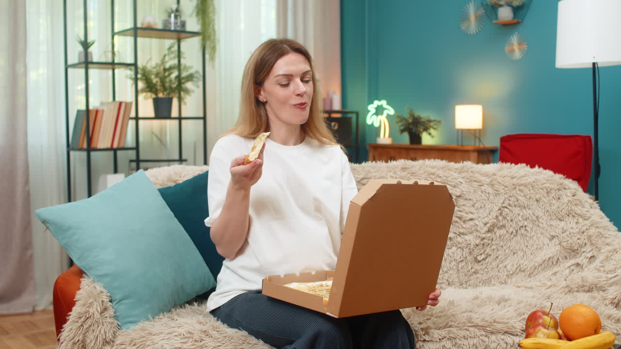 Pregnant woman opens pizza box smells slice bites piece smiling tasting dinner indoors supper time