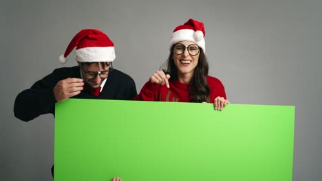 Pareja-Nerd-Apuntando-A-Un-Cartel-Con-Ropa-De-Navidad