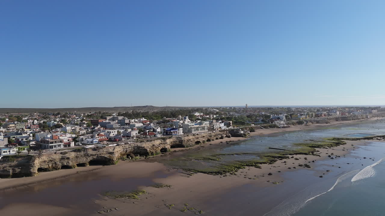 Experience a mesmerizing aerial panning view of Las Grutas coastline, highlighting the dynamic cityscape and scenic beauty of Argentina's shores.