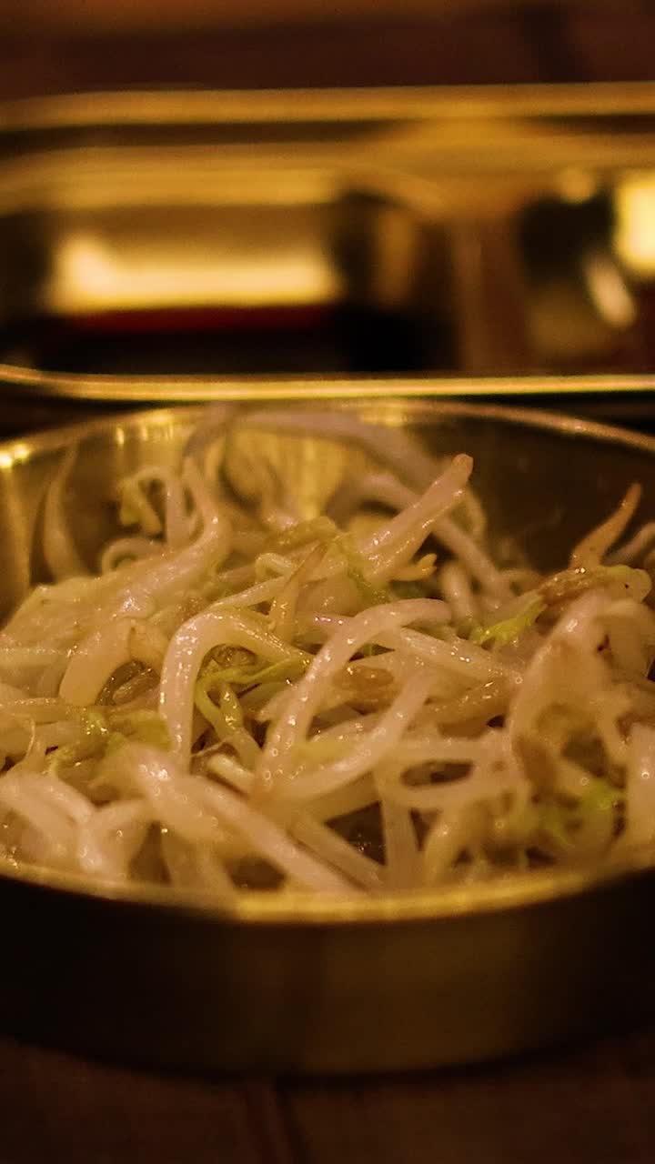 Bacchette che sollevano germogli di fagioli mung da una ciotola