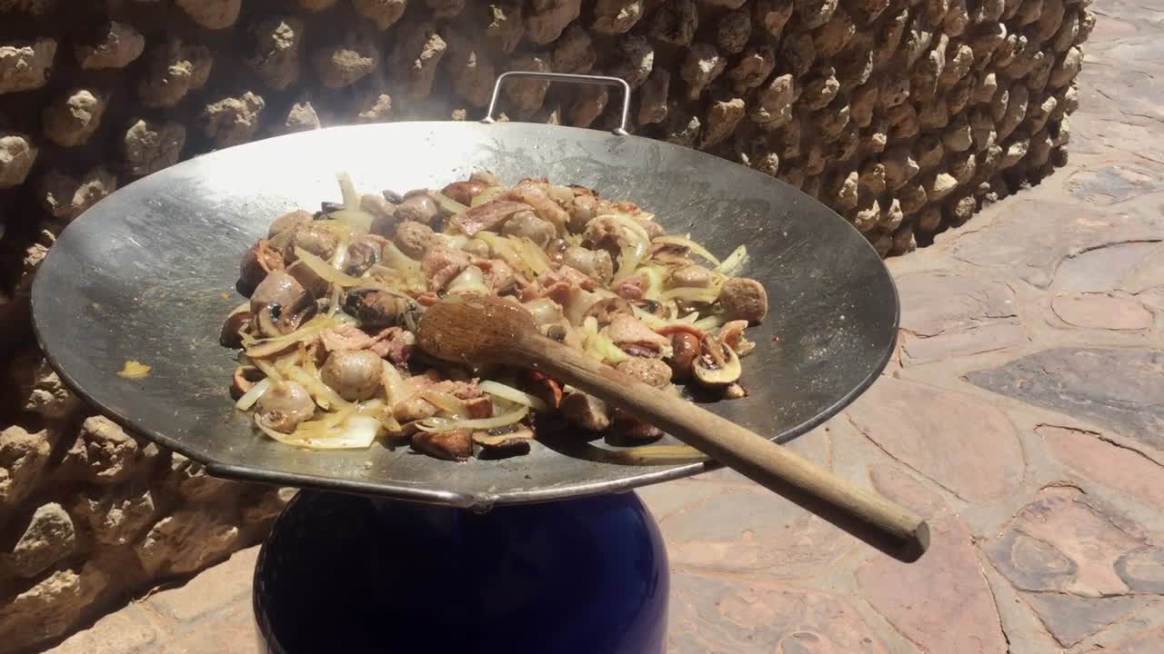 salteado de pollo chisporroteante en un wok enorme, con una cuchara grande de madera