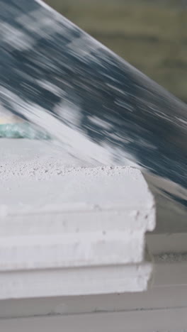skilled plasterer in gloves saws white gypsum plasterboard professionally and removes dust close view