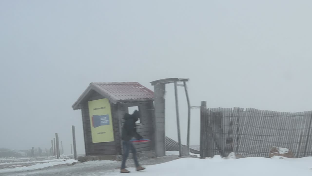 Driving Passed People With Jackets In a Stark Winter Landscape During a Snowy, Foggy Day