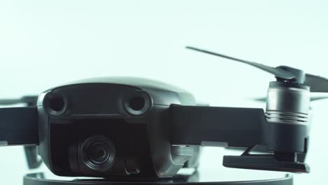 toma de primer plano de un dron con lente de cámara y hélices, color gris plateado, en un soporte giratorio de 360, cámara lenta, iluminación de estudio, video de 4k