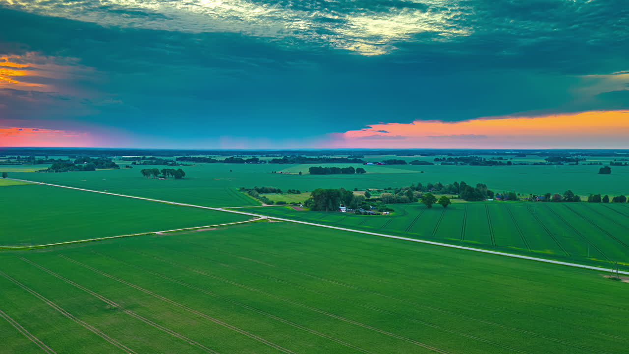 Udsigt til rødgylden himmel ved solnedgang fra drone, luftfoto af grønt landskab i time-lapse