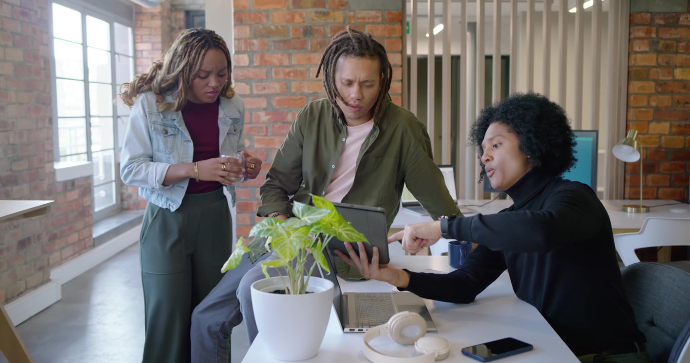 African American team with man passing tablet, woman pointing at screen, deciding project at office