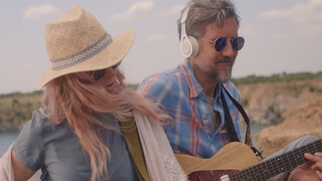 couple playing acoustic guitar by the lake