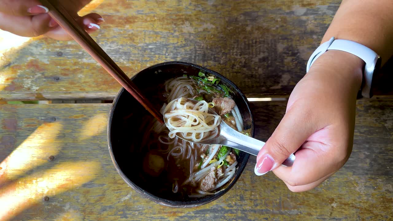 mujer comiendo sopa de fideos de carne de res