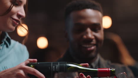 diverse-friends-celebrating-reunion-party-in-restaurant-waitress-pouring-wine-serving-group-enjoying-friendship-celebration-having-fun-together