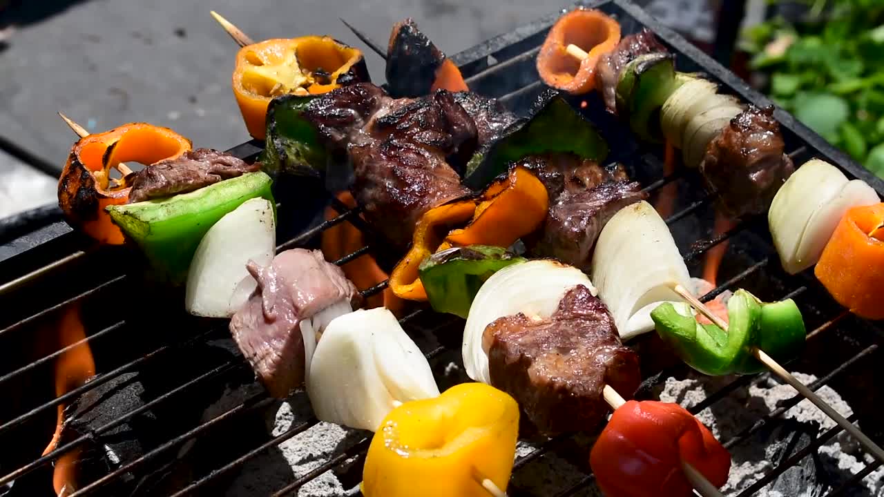 brochetas de carne y verduras sobre briquetas de carbón caliente a la parrilla al aire libre