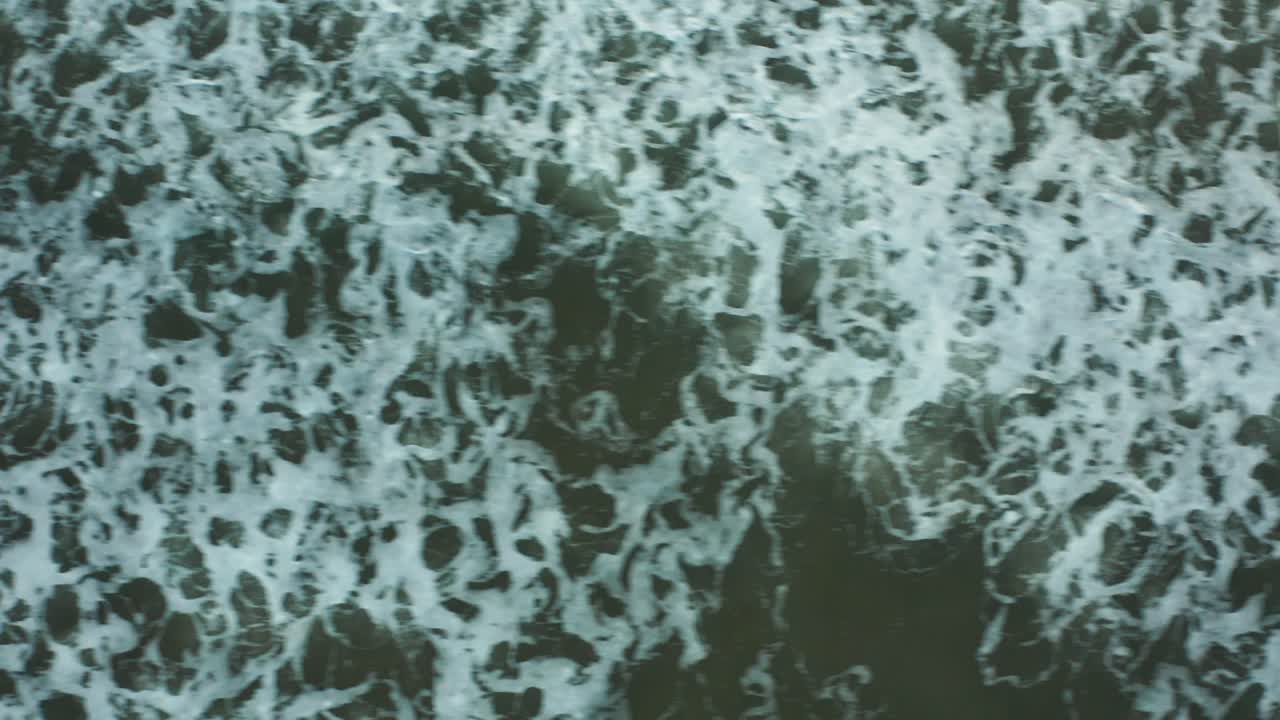 un dron disparó sobre aguas poco profundas mientras las olas chocaban, formando hermosos patrones