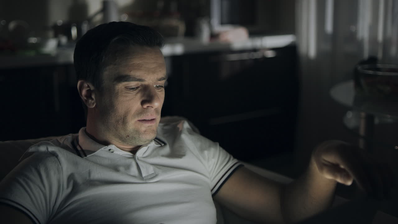 Nærbilde av hardtarbeidende mann som gjesper foran bærbar PC-en på kontoret om natten