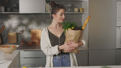 woman holding a bag of groceries in a kitchen