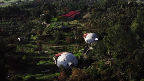 drone shot of sun drenched hilly landscape with rolling mist, forest and small buildings