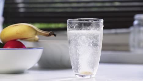 disparo de un vaso de agua en el que una persona deja caer una tableta de vitamina gaseosa
