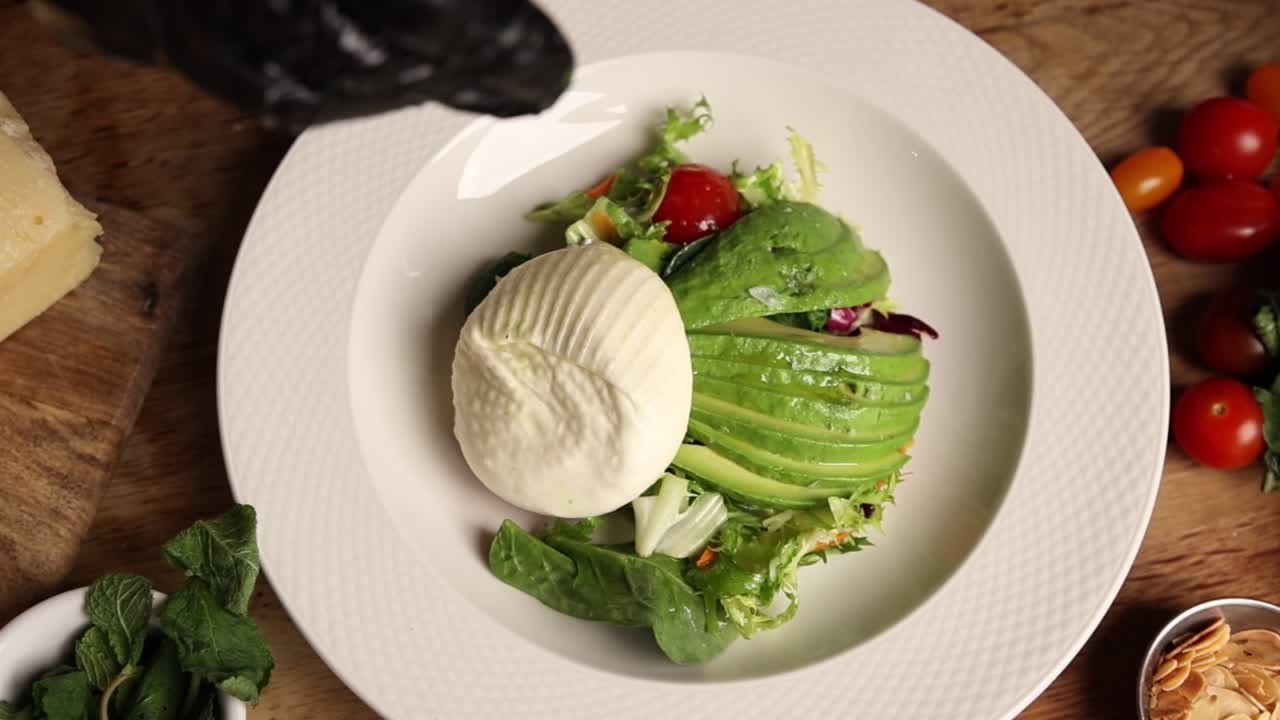 Chef Plating Fresh Burrata and Avocado Salad