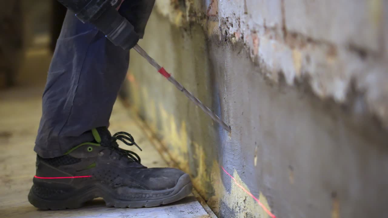 Worker drilling a wall with a laser guide during a restoration project