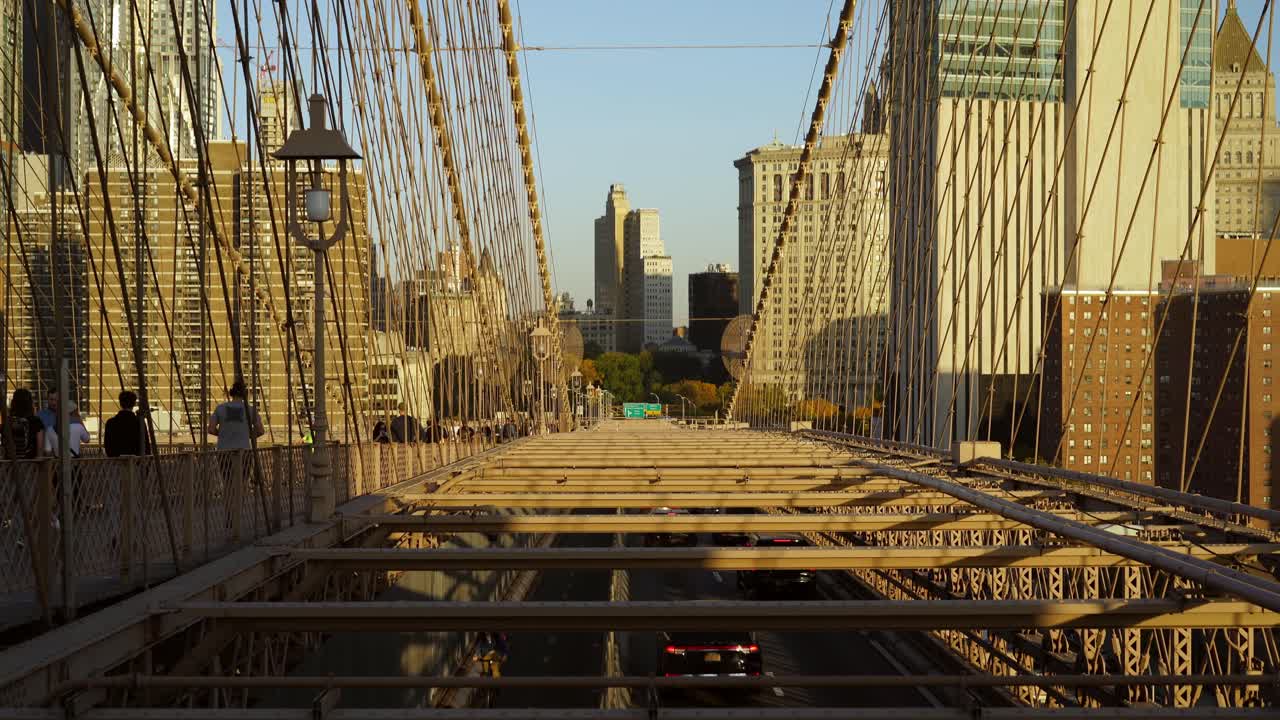Busy Cars Traffic through Brooklyn Bridge to Lower Manhattan on a Sunny Evening in New York with Buildings in the Distance