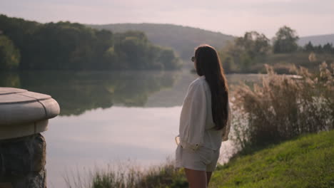 woman relaxing by a lakeside at sunset