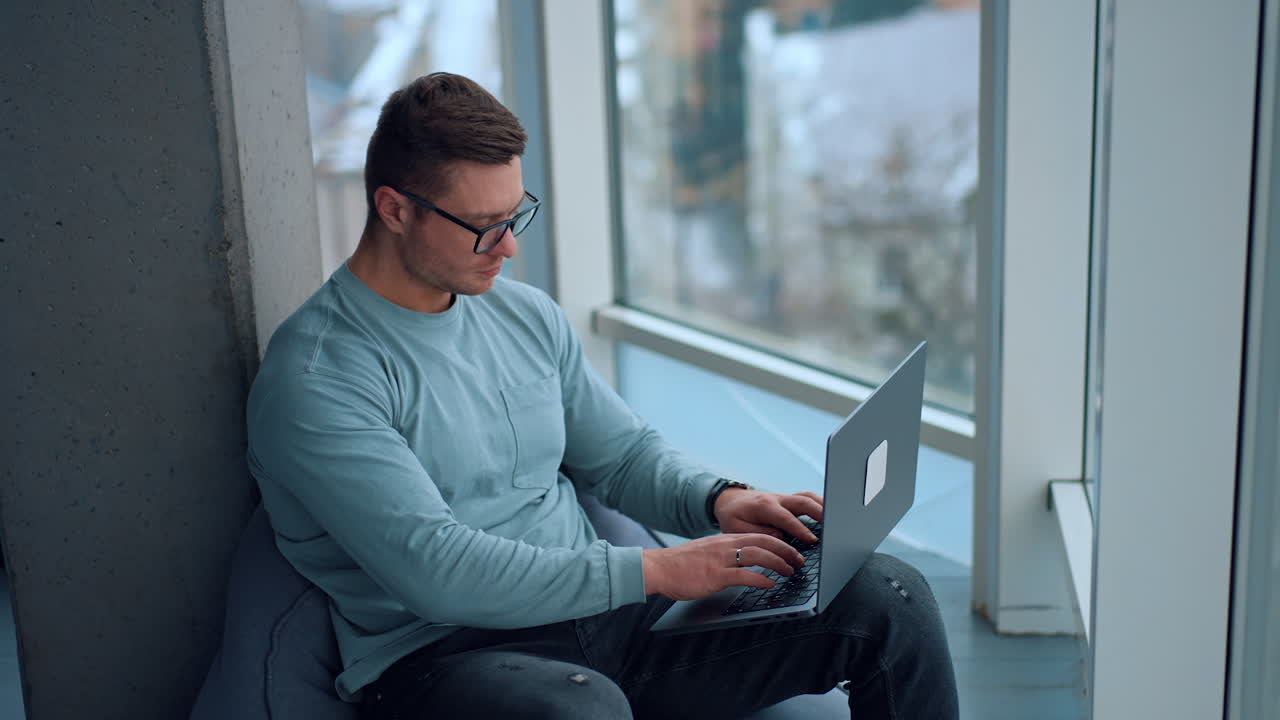 hombre trabajando en una computadora portátil por la ventana