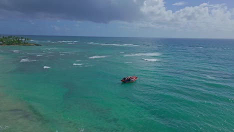 Red-fishing-boat-anchored-in-turquoise-water-of-Pepillo-Salcedo-beach,-Cabrera