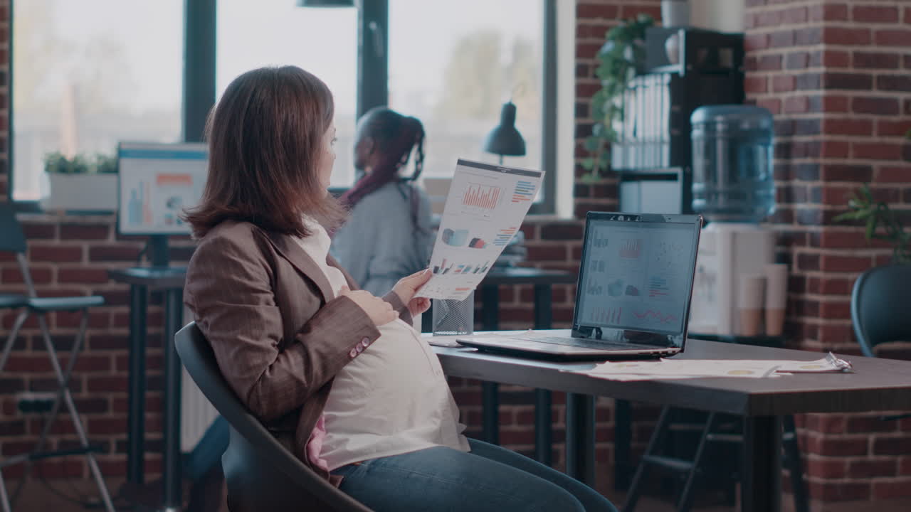 Pregnant woman using laptop to work on business project in office