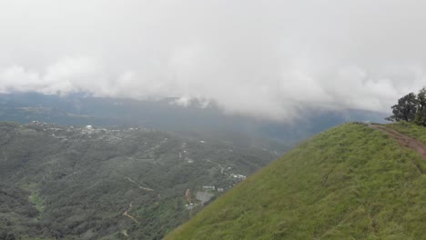 toma aérea de 4k de un hombre indio de 25 años corriendo hacia la cima y revelando la aldea de shirui desde la cima del pico de shirui, ukurul, manipur, india