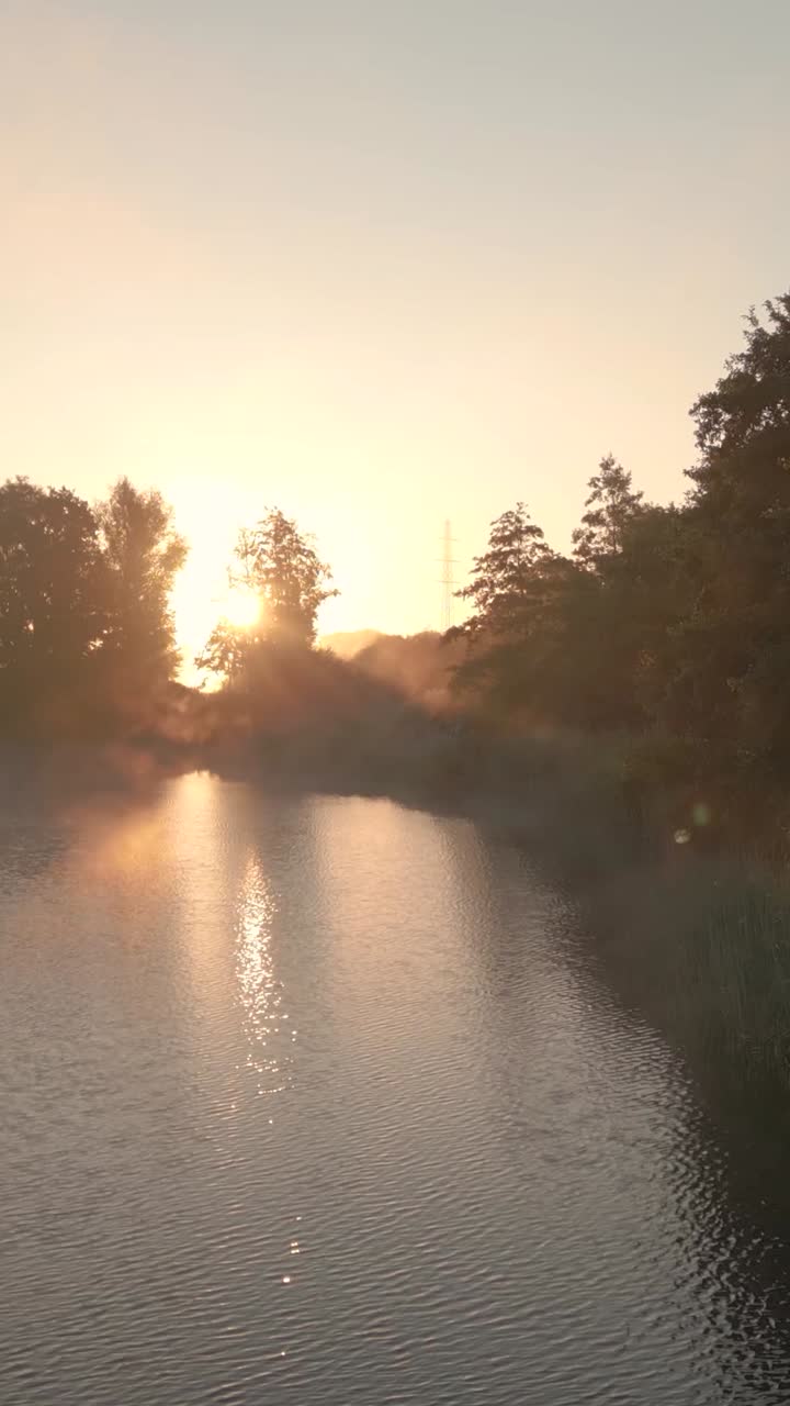 Východ slunce nad řekou a krajinou