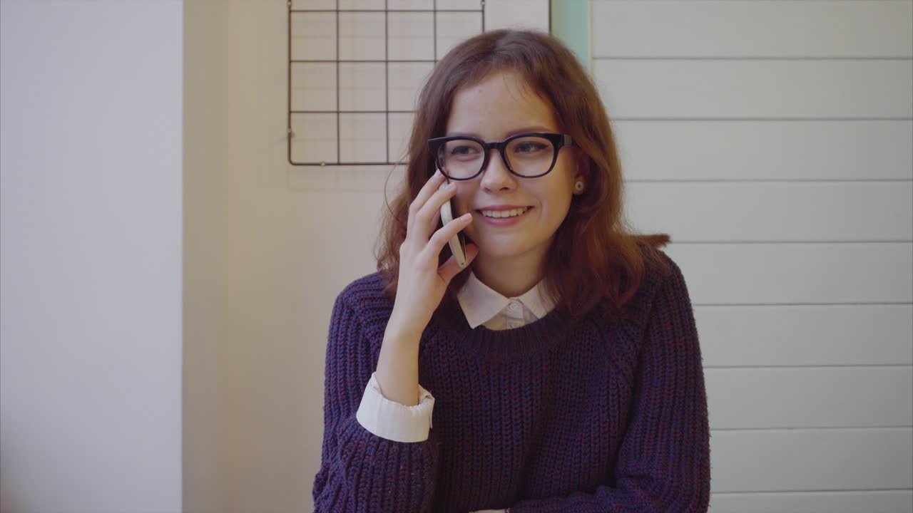 una adolescente hablando por teléfono en un café.