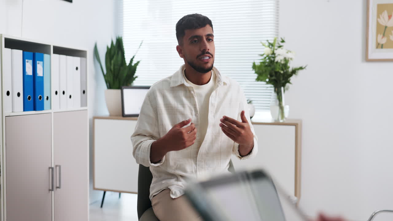 Young Man Talking and Gesturing in a Modern Office Setting