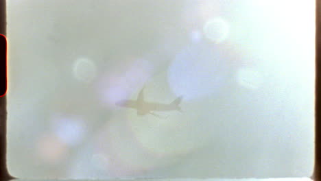 filmed on super 8 film - airplane traversing cloudy skies, capturing nostalgic super 8 film aesthetic with atmospheric lens flare and evocative light leaks in classic documentary style